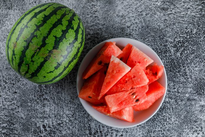 Watermelon with slices on grey grunge background, flat lay. arbuz