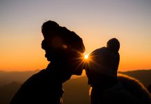 Chwila czułości dwóch osób na tle złotego zachodu słońca.