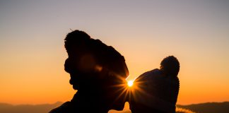 Chwila czułości dwóch osób na tle złotego zachodu słońca.