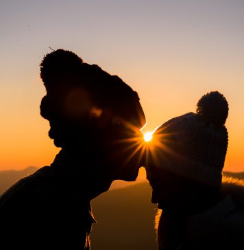 Chwila czułości dwóch osób na tle złotego zachodu słońca.
