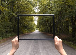 Osoba stojąca na drodze, trzymająca przed sobą pustą ramkę