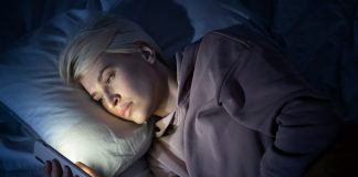 Kobieta leżąca w łóżku i korzystająca z telefonu