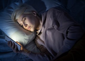 Kobieta leżąca w łóżku i korzystająca z telefonu