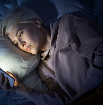 Kobieta leżąca w łóżku i korzystająca z telefonu