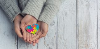 Dłonie trzymające kolorowe serce z puzzli