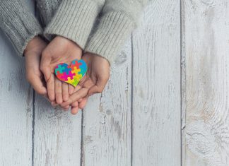 Dłonie trzymające kolorowe serce z puzzli