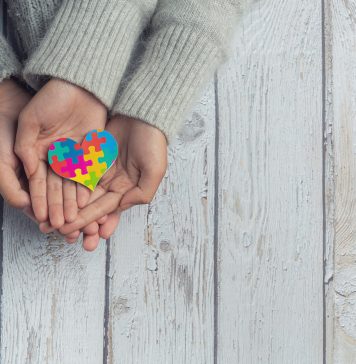 Dłonie trzymające kolorowe serce z puzzli