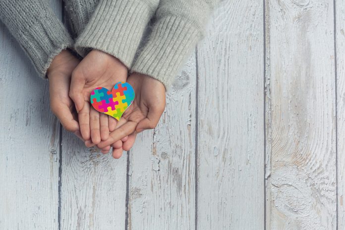 Dłonie trzymające kolorowe serce z puzzli