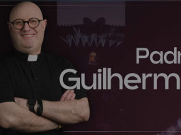 Uśmiechnięty męzczyzna w okrągłych okularach i koszule z koloratką na tle zdjęcia sceny festiwalowej. Napis Padre Guilherme