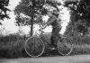 Rowerzysta jadący na rowerze w otoczeniu drzew – czarno-biała fotografia.