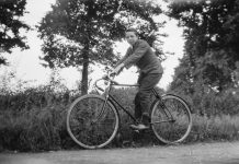 Rowerzysta jadący na rowerze w otoczeniu drzew – czarno-biała fotografia.