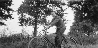 Rowerzysta jadący na rowerze w otoczeniu drzew – czarno-biała fotografia.