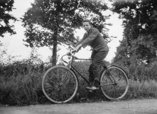 Rowerzysta jadący na rowerze w otoczeniu drzew – czarno-biała fotografia.