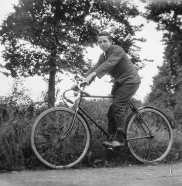 Rowerzysta jadący na rowerze w otoczeniu drzew – czarno-biała fotografia.