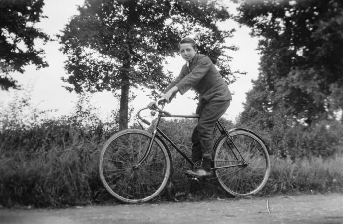 Rowerzysta jadący na rowerze w otoczeniu drzew – czarno-biała fotografia.