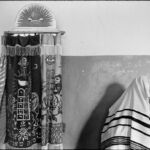 Polish Jews 1979
Roll 29 frame 13a.  Saying the blessing for donning the tallit at morning services in the only Beit Midrash (prayer room) in Warsaw, adjacent to the unused Nozyk synagogue. The Nozyk synagogue, the only one to survive WWII, is unused because it is too big and cold for the few people who come to pray.  January 1979. Chuck Fishman Re-Generation