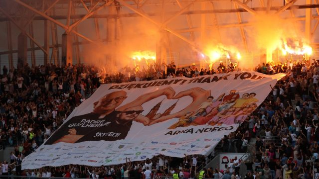 Tłum bawiący się pod sceną koncertu W górę serca na stadionie w Opolu. Wznoszą wielki baner ze zdjęciami artystów i słowami "dziękujemy"